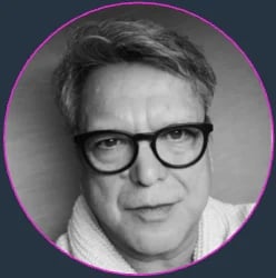 Black and white portrait of a man wearing glasses with dark hair, shown in a circular frame with purple border